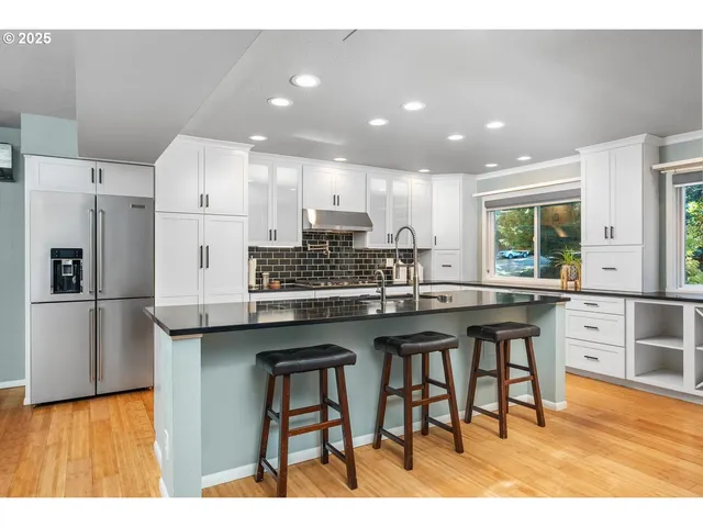 a kitchen with stainless steel appliances granite countertop a table chairs sink refrigerator and cabinets