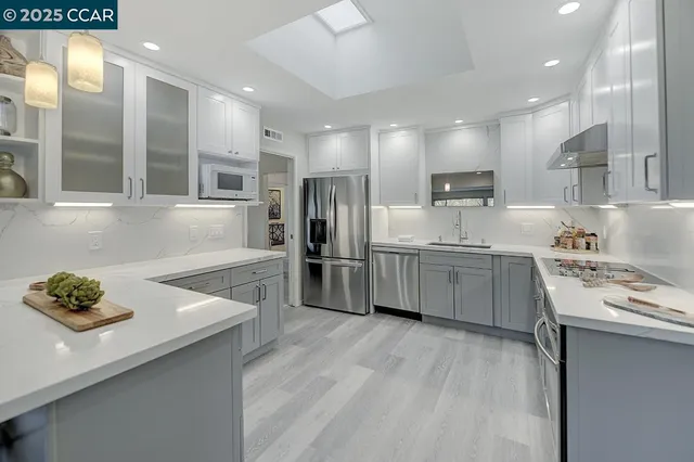 a kitchen with stainless steel appliances a sink a stove a refrigerator cabinets and a counter top space