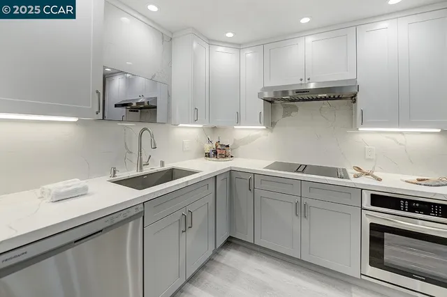 a kitchen with a sink white cabinets and stainless steel appliances
