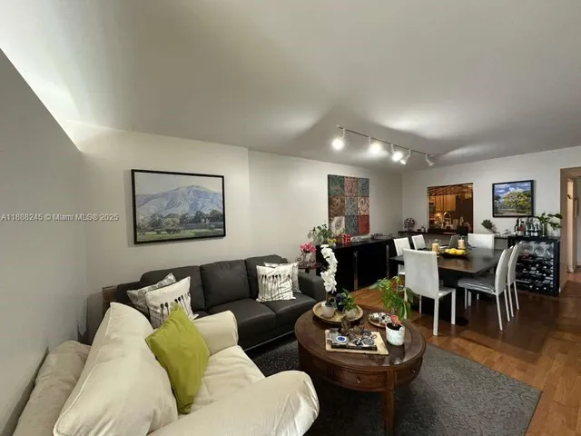 a living room with furniture potted plant kitchen view and a window