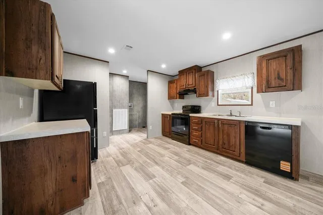 a kitchen with stainless steel appliances granite countertop a refrigerator a sink dishwasher a stove and a microwave oven on granite countertops