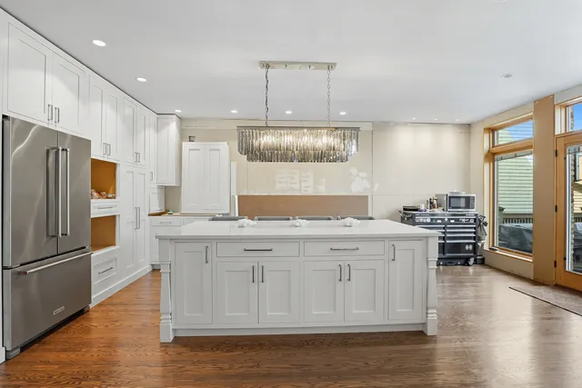 a kitchen with stainless steel appliances granite countertop a refrigerator a sink dishwasher a stove and white cabinets with wooden floor