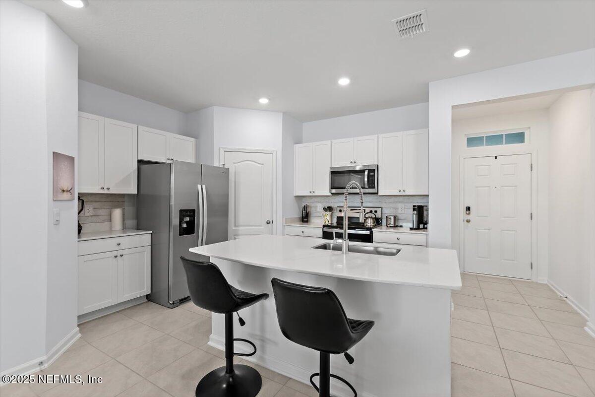 120 Seaport Breeze Rd Street St. Augustine, FL 32095 - Photo 4 of 25 a kitchen with stainless steel appliances a refrigerator stove microwave and cabinets