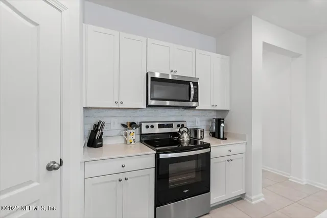 a kitchen with white cabinets and black appliances