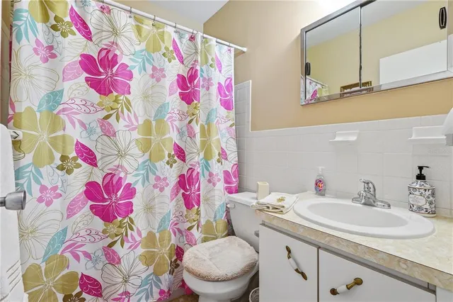 a bathroom with a sink toilet vanity and curtain