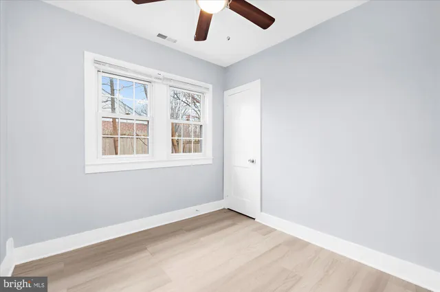 an empty room with a window and a ceiling fan