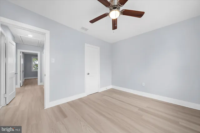 an empty room with wooden floor and a ceiling fan