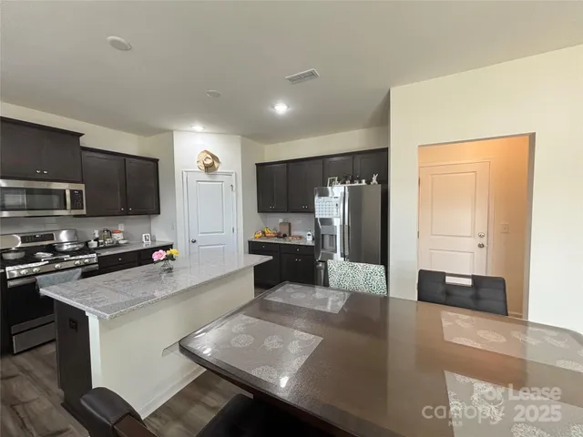 a kitchen with stainless steel appliances a stove a refrigerator a sink a stove a oven with white cabinets and wooden floor