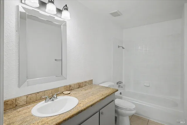 a bathroom with a granite countertop sink toilet a mirror and bathtub
