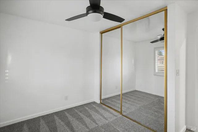 an empty room with ceiling fan and windows