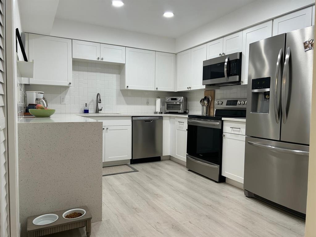 16325 Golf Club Road, Unit 109 Weston, FL 33326 - Photo 4 of 20 a kitchen with a sink stainless steel appliances and white cabinets
