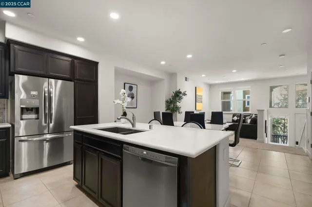 a kitchen with stainless steel appliances kitchen island granite countertop a refrigerator a sink a stove and white cabinets with wooden floor