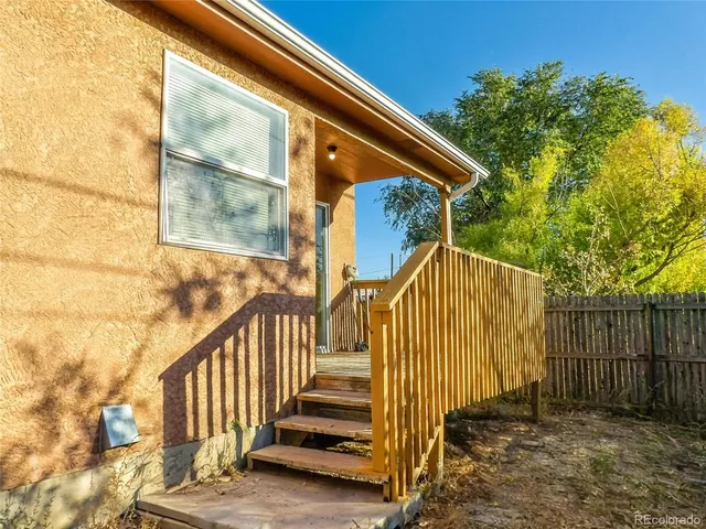 a view of backyard with wooden fence and large trees