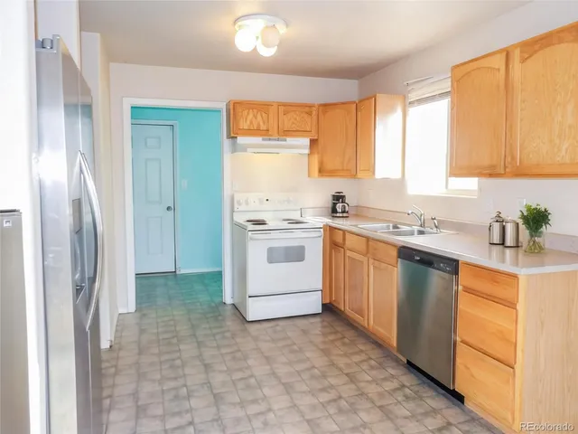 a kitchen with a stove a sink dishwasher a refrigerator and cabinets