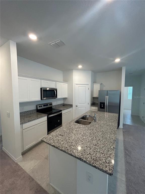 5873 Beefmaster Road St. Cloud, FL 34771 - Photo 6 of 16 a kitchen with stainless steel appliances granite countertop a sink stove and refrigerator
