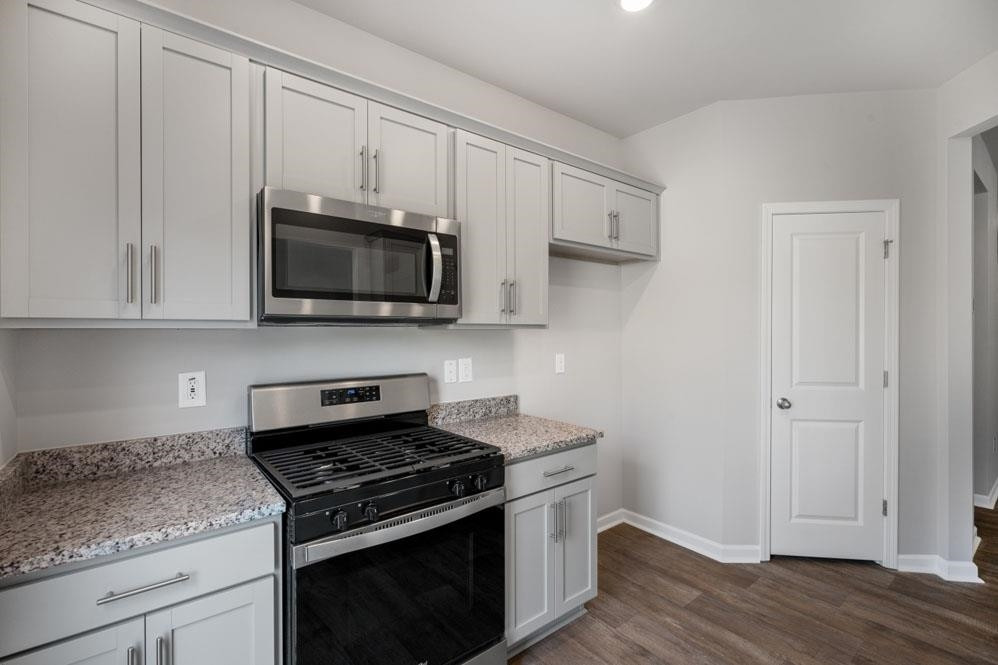 115 Starlight Street Sanford, NC 27330 - Photo 10 of 37 a kitchen with stainless steel appliances granite countertop a stove a microwave and a white cabinets