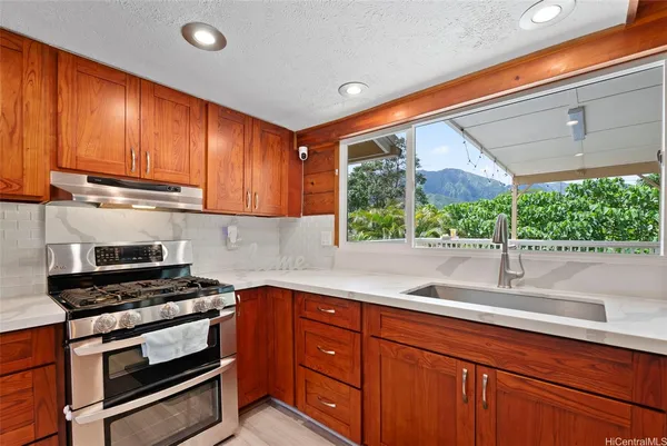 a kitchen with granite countertop cabinets stainless steel appliances and a large window