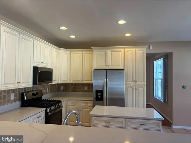 a kitchen with stainless steel appliances granite countertop a refrigerator a stove and a sink