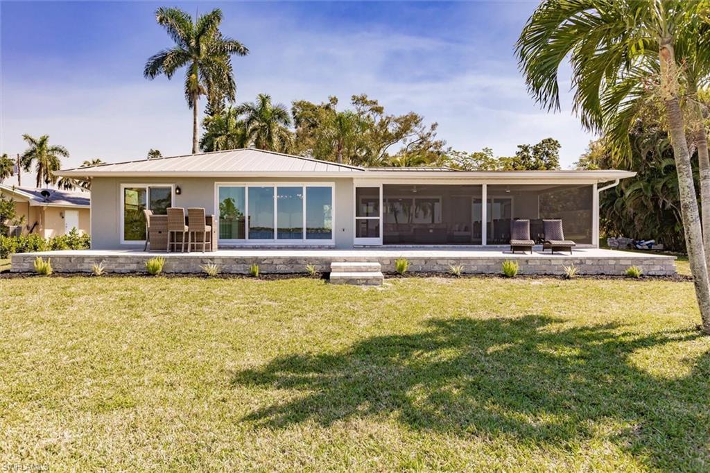 138 Riverview Road Fort Myers, FL 33905 - Photo 41 of 50 Back of house with a patio area, a sunroom, and a yard