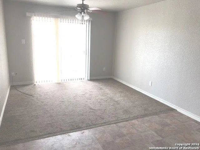 a view of a refrigerator in kitchen and an empty room