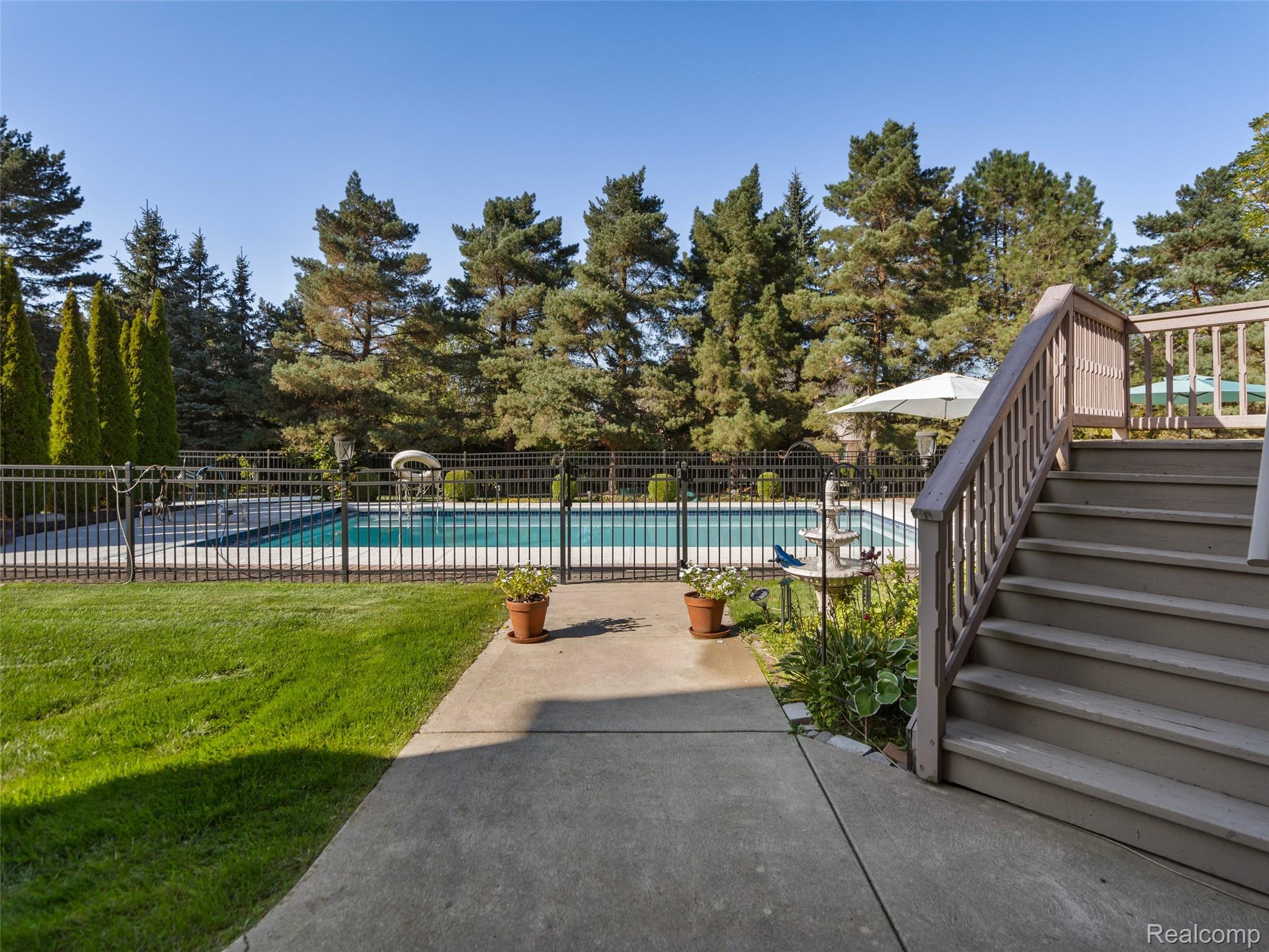 5724 Murfield Drive Rochester, MI 48306 - Photo 23 of 99 View of swimming pool featuring stairway, view of wooded area, and a patio