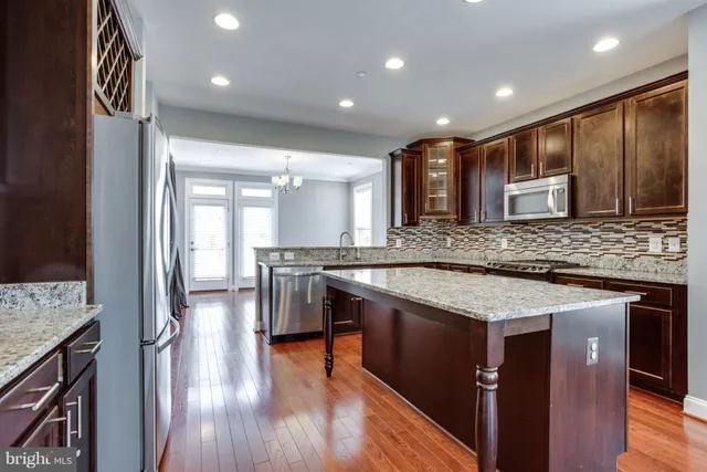 a kitchen with stainless steel appliances granite countertop wooden cabinets and wooden floor