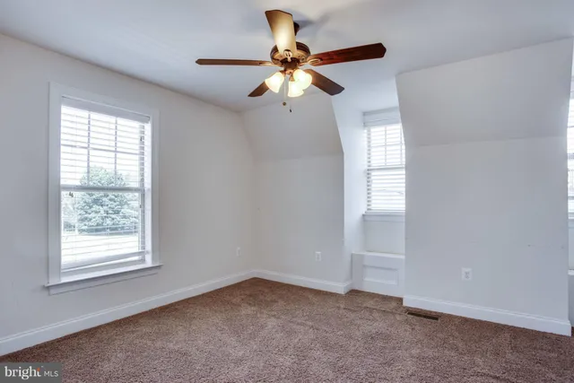 an empty room with windows and fan
