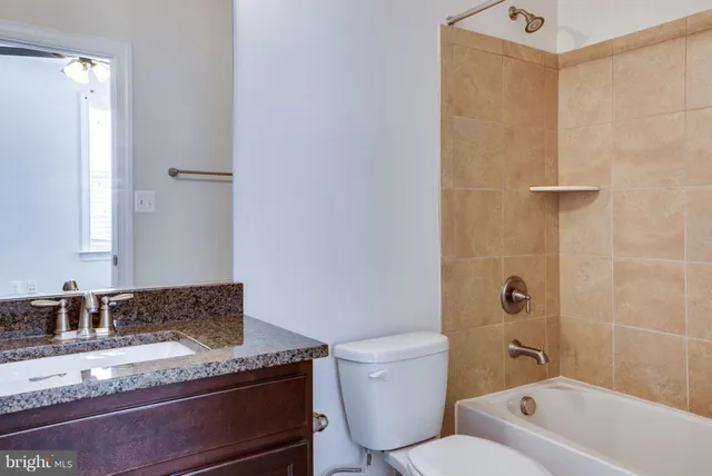 a bathroom with a granite countertop sink a toilet and shower