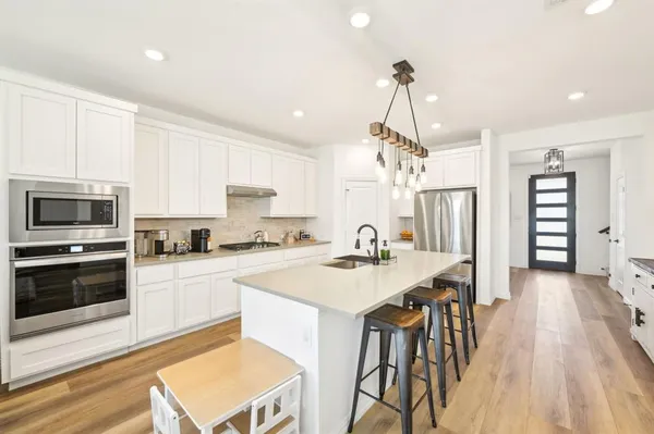 a kitchen with a table chairs stainless steel appliances and cabinets