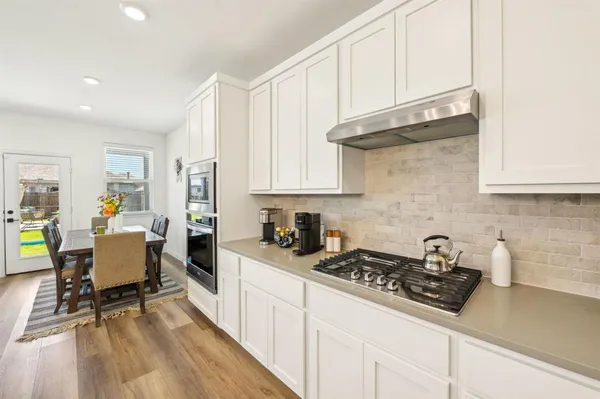 a kitchen with stainless steel appliances granite countertop a stove a sink dishwasher and cabinets with wooden floor