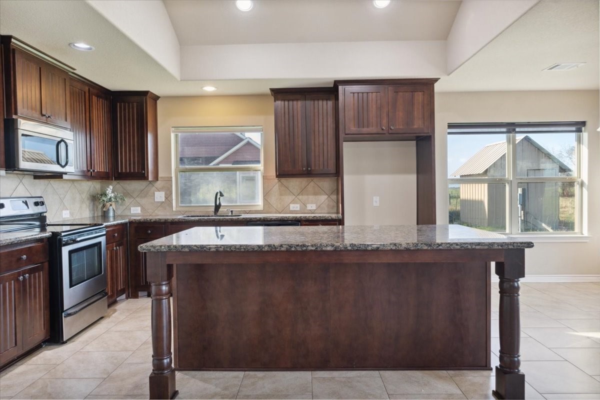 2407 Thuesen Road Beasley, TX 77417 - Photo 13 of 34 a kitchen with kitchen island granite countertop a stove a sink and a microwave