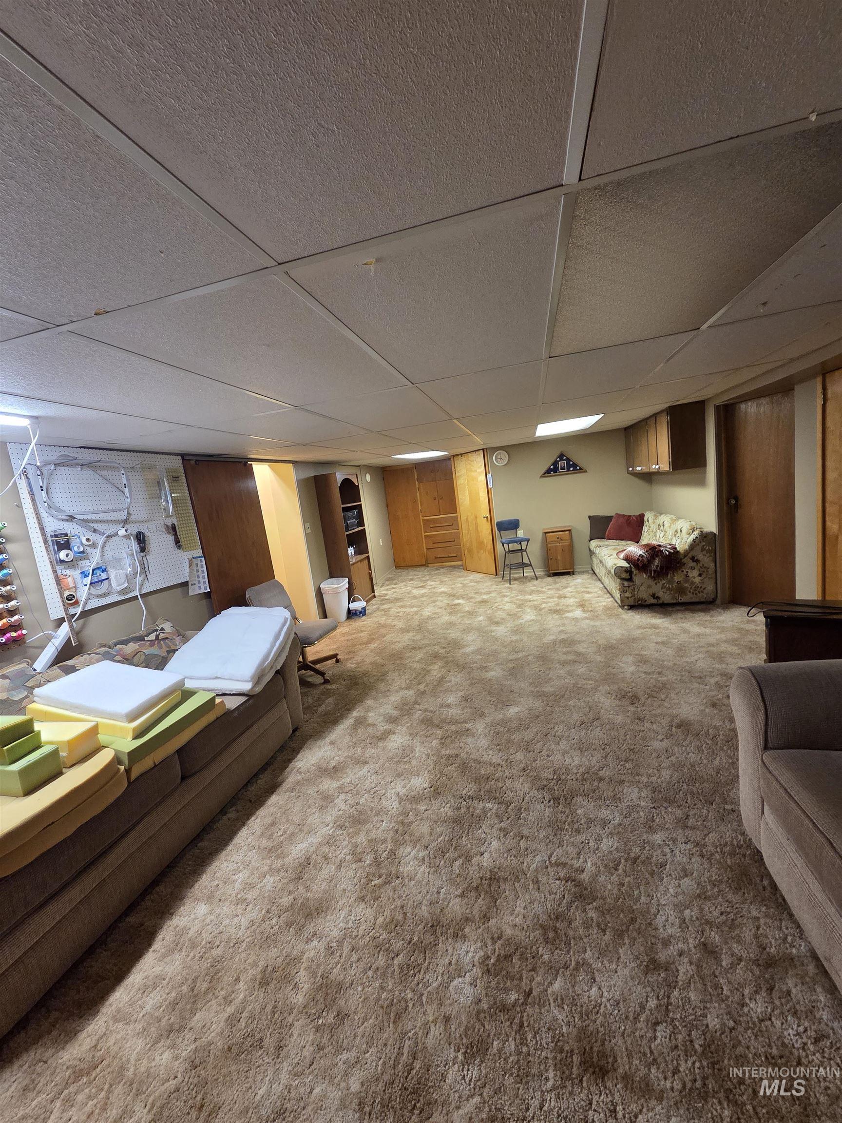109 South 3rd Street Pomeroy, WA 99347 - Photo 22 of 36 Expansive carpeted area featuring a drop ceiling with integrated lighting, wood-finish paneling, and built-in cabinetry