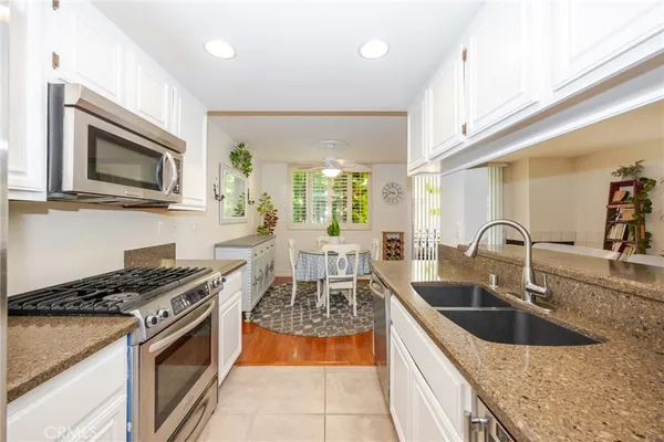 a kitchen with stainless steel appliances granite countertop a stove a sink and a microwave