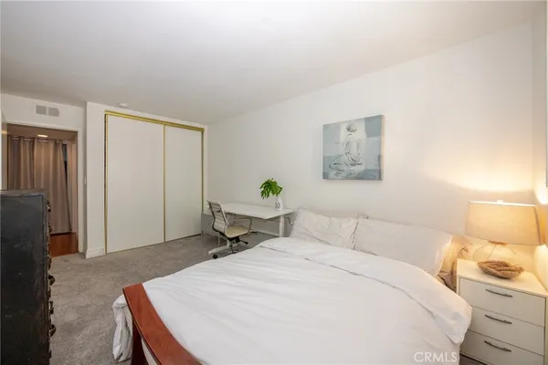 a bedroom with a bed and a lamp on the dresser