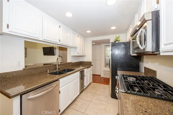 a kitchen with granite countertop stainless steel appliances a sink a stove cabinets and a counter top space