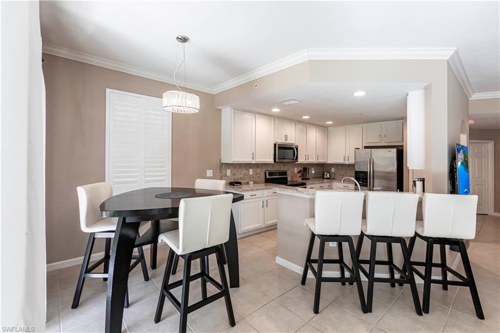 9508 Ironstone Terrace, Unit 2102 Naples, FL 34120 - Photo 17 of 50 a dining room with stainless steel appliances kitchen island granite countertop a dining table chairs and a refrigerator