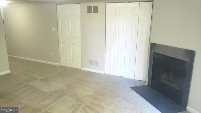 a view of an empty room with wooden floor and a fireplace