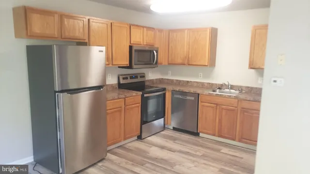 a kitchen with stainless steel appliances granite countertop a refrigerator stove a sink and dishwasher with wooden floor