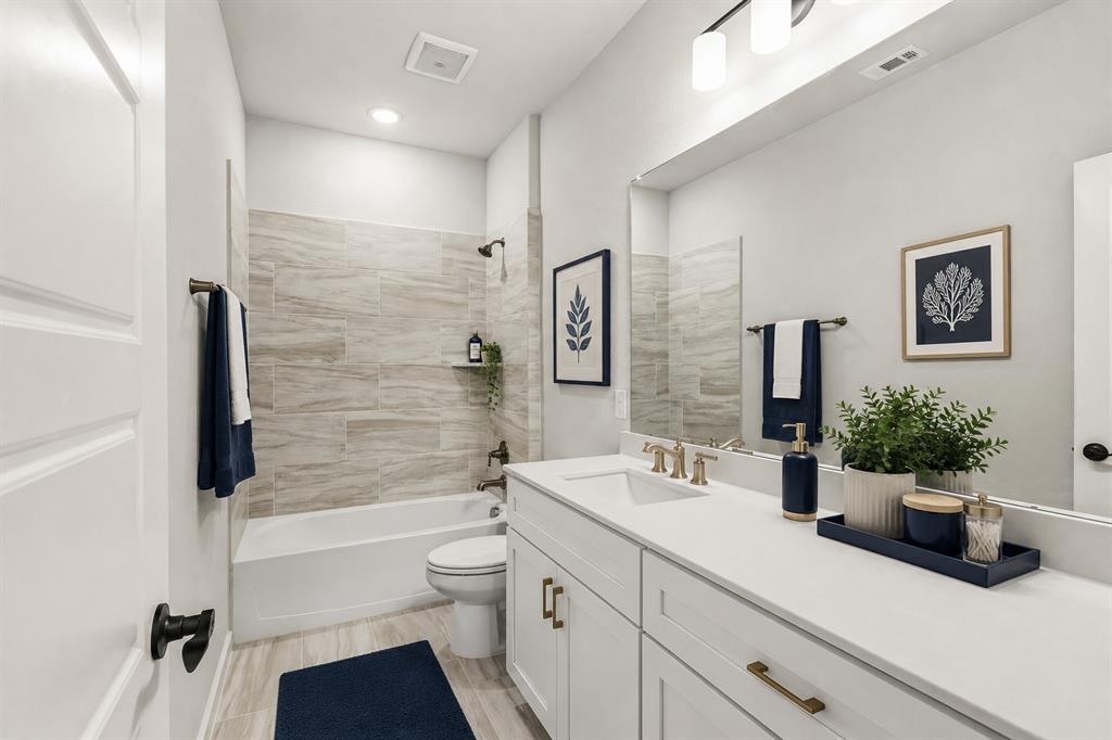 3311 Willena Road Melissa, TX 75454 - Photo 19 of 40 Contemporary bathroom featuring a white vanity with gold-finish hardware, a large wall-mounted mirror, and a tub-shower combination with tiled surround