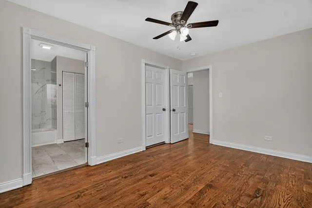 an empty room with wooden floor and a ceiling fan