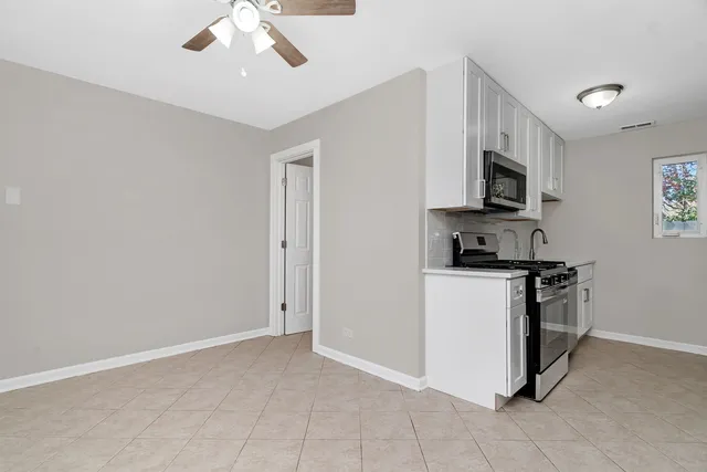 a kitchen with stainless steel appliances granite countertop a refrigerator a stove a microwave oven with white cabinets