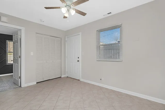 an empty room with windows and fan