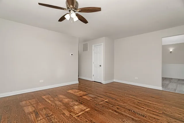 a view of a room with wooden floor and a ceiling fan