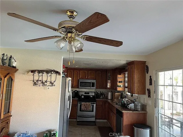 a kitchen with stainless steel appliances kitchen island granite countertop a refrigerator a stove a microwave oven with a dining table and chairs
