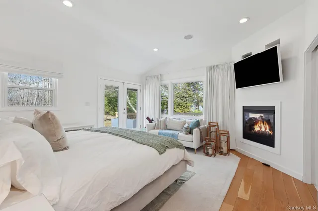 a bedroom with a large bed a flat tv screen and a fireplace