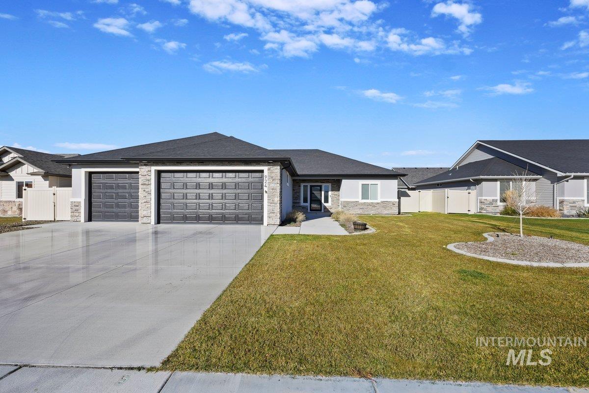 View of front of property featuring a gate, stone siding, an attached garage, and concrete driveway