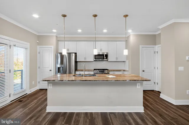 a kitchen with kitchen island stainless steel appliances a sink and wooden floor