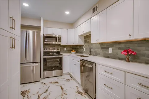 a kitchen with granite countertop white cabinets and stainless steel appliances