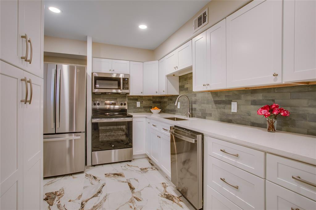 7777 Royal Lane Dallas, TX 75230 - Photo 13 of 30 a kitchen with granite countertop white cabinets and stainless steel appliances