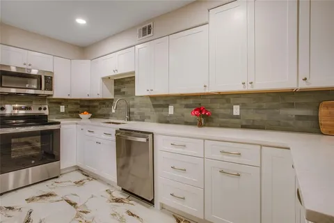 a kitchen with granite countertop white cabinets stainless steel appliances and a sink